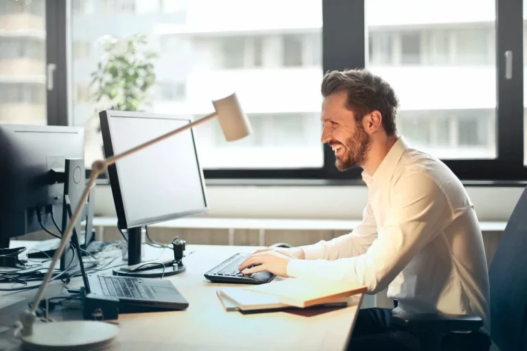 A man in a white shirt, uising a desktop computer